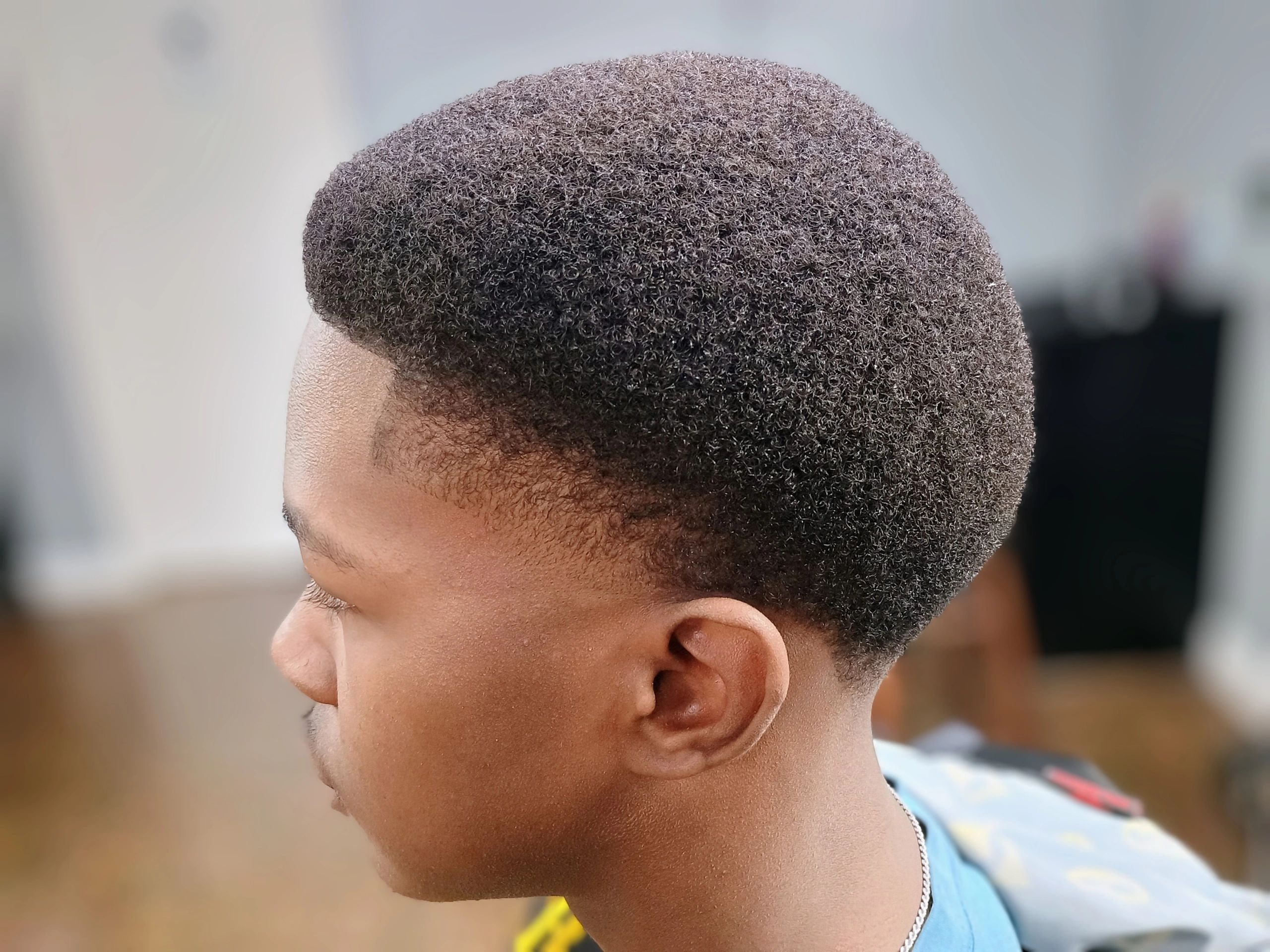 Man with a short textured fade haircut and clean neckline at JW Barbershop