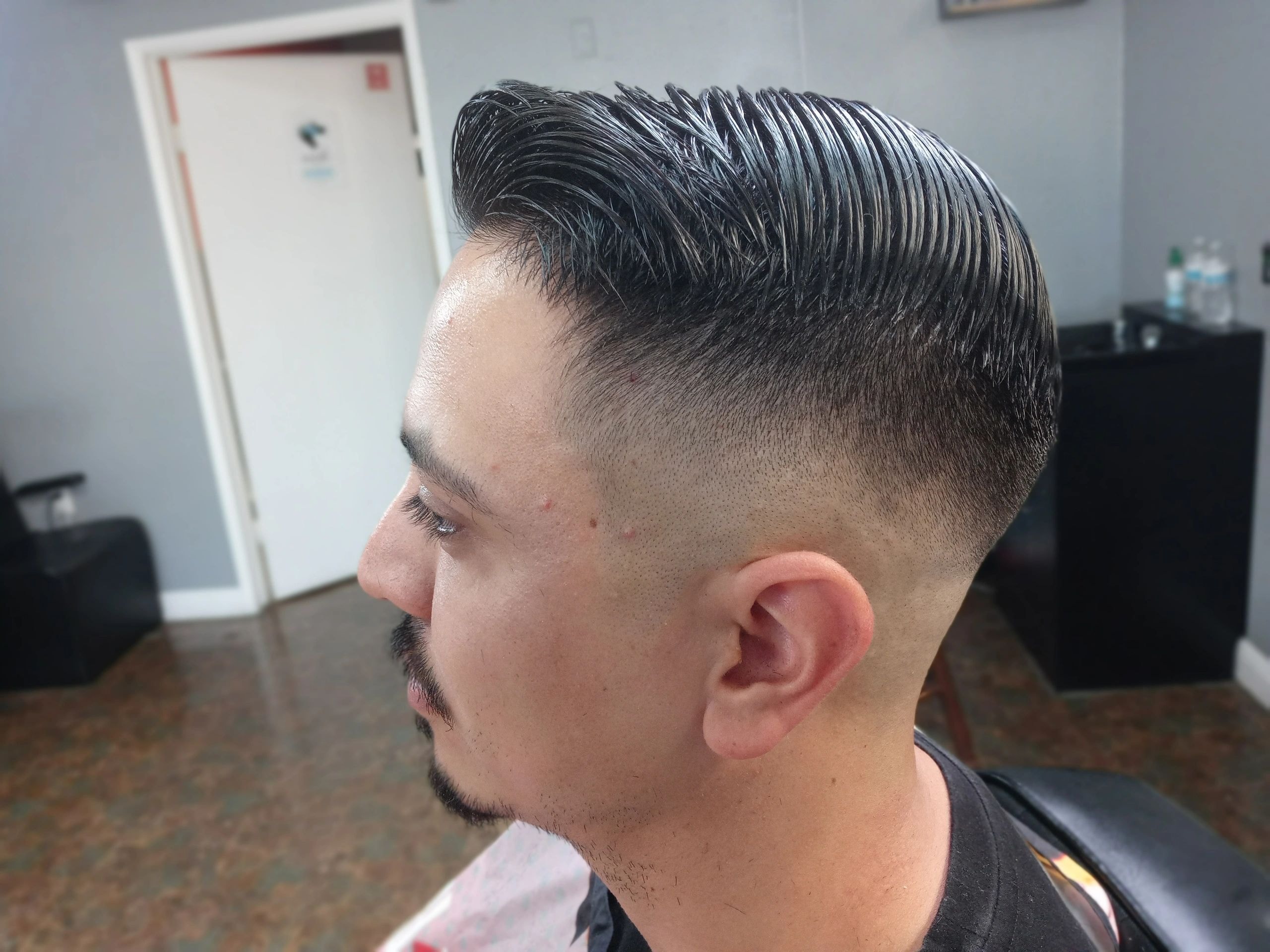 Man with a slick back undercut hairstyle with a high fade at JW Barbershop